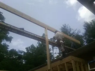 Carpenter setting a ridge beam over a new addition frame — Ice Dam Removal by Roofing Brothers in Metropolis