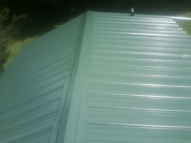 New green metal panels meeting at the ridge of a roof — Flat Roof Repair work by our crew in Metropolis