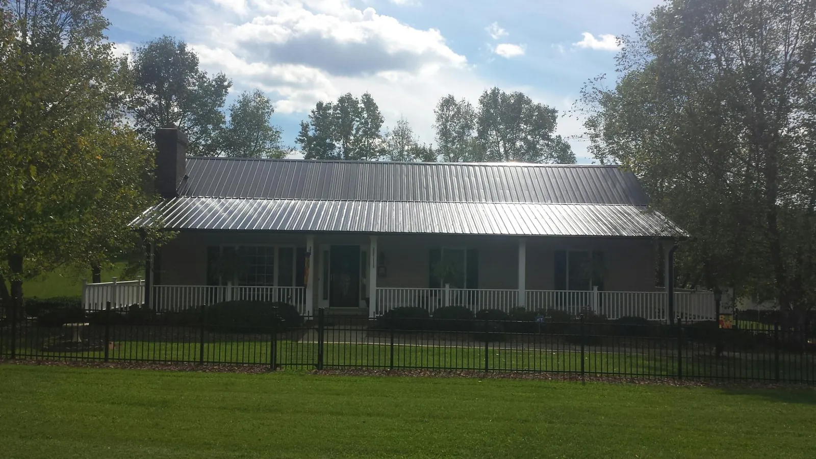 Gray metal roof on a brick ranch with a full width front porch — Gutter Guard Installation work by our crew in Metropolis